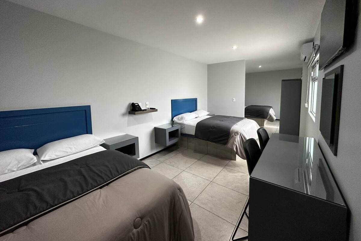 A hotel room with two beds, a desk, and a chair.