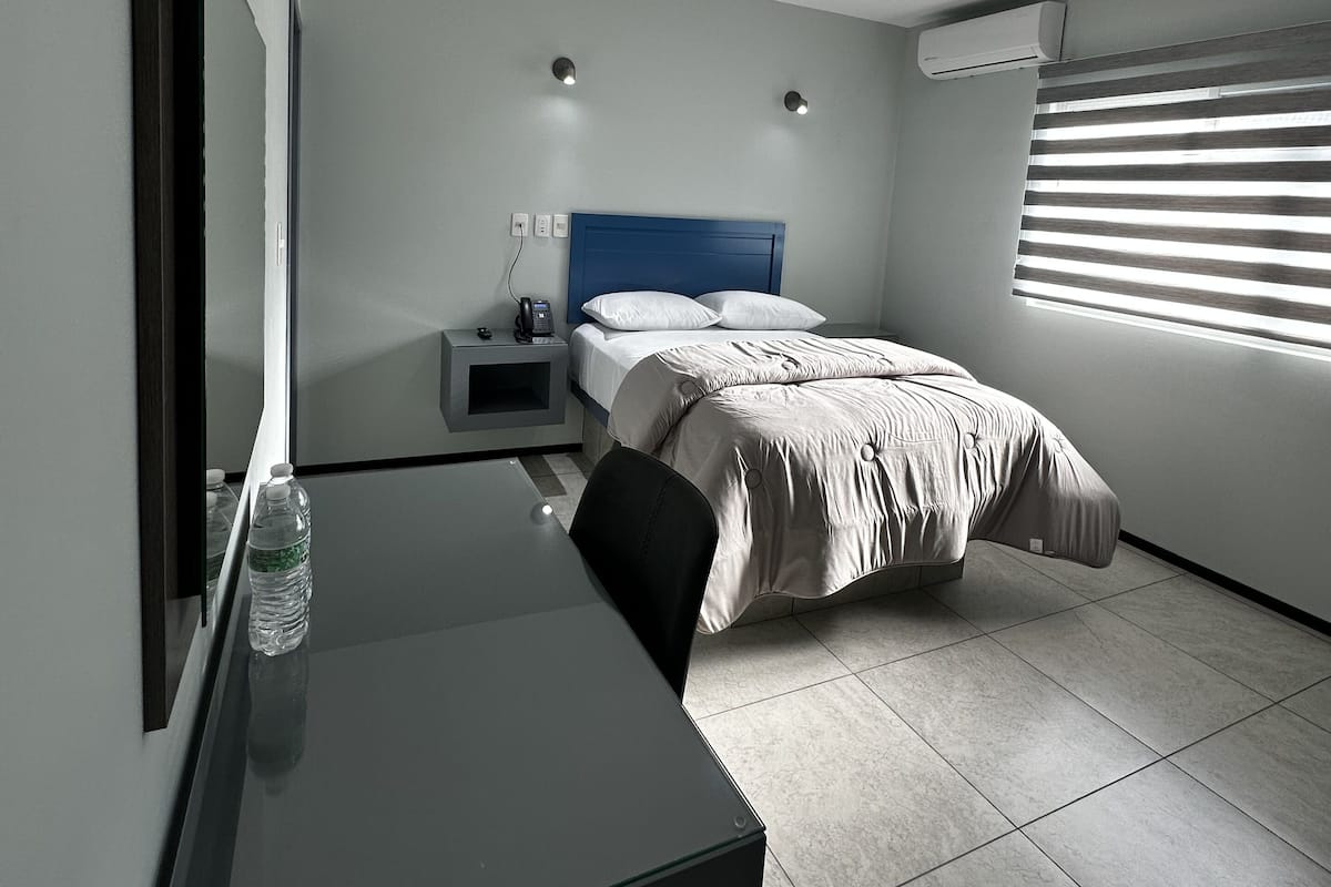 A modern hotel room with a bed, a desk, and a television.