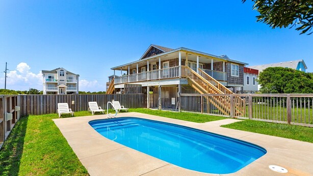 A two-story house with a swimming pool, a covered deck, and a staircase leading to the upper level.