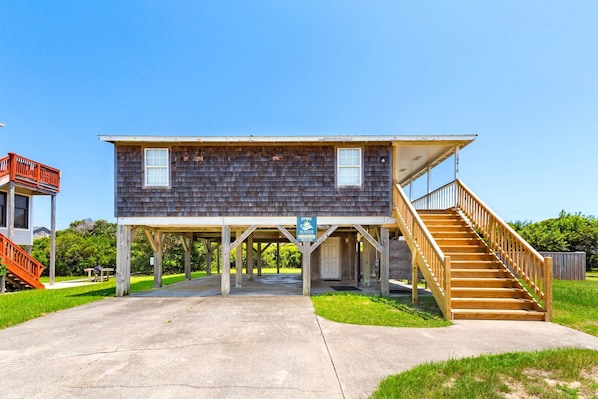 A two-story wooden building with a balcony and a staircase leading to a deck. - Sandcastle - 500ft to Beach w/ pool (Nags Head)