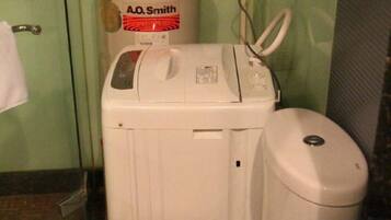 Una lavadora blanca con panel de control y un bote de basura blanco en un baño.