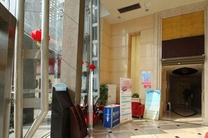 A hotel lobby with a reception desk, a large mirror, potted plants, and a red lantern. - Yasi Apartment Hotel (Shanghai)