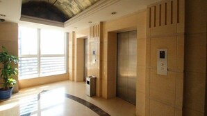 An interior with an elevator, a trash bin, and a potted plant. - Yasi Apartment Hotel (Shanghai)
