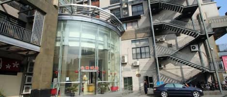 A multi-story building with a glass entrance, outdoor seating, and a fire escape.