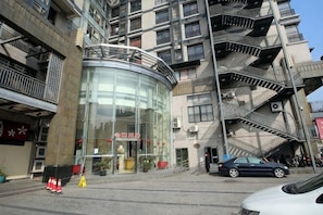 Un immeuble à plusieurs étages doté d’une façade en verre, d’une entrée bien visible et d’un escalier menant à un niveau supérieur.