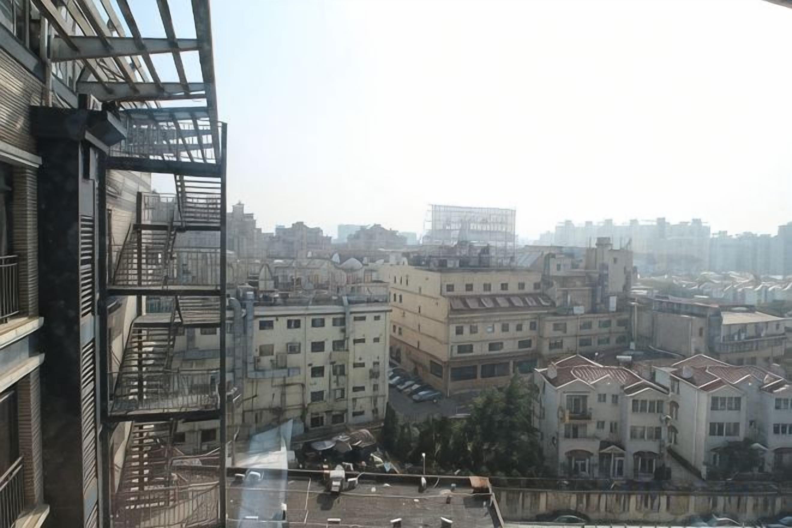 A high-rise building with multiple balconies and a view of a cityscape.