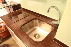 A kitchen with a stainless steel sink, a glass backsplash, and a modern faucet. - Yasi Apartment Hotel (Shanghai)