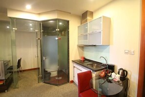 A compact kitchen with a glass partition, a red chair, and a coffee machine. - Yasi Apartment Hotel (Shanghai)
