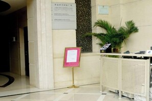 Un espace d’accueil comprenant un comptoir de réception, une plante en pot et un panneau d’affichage.