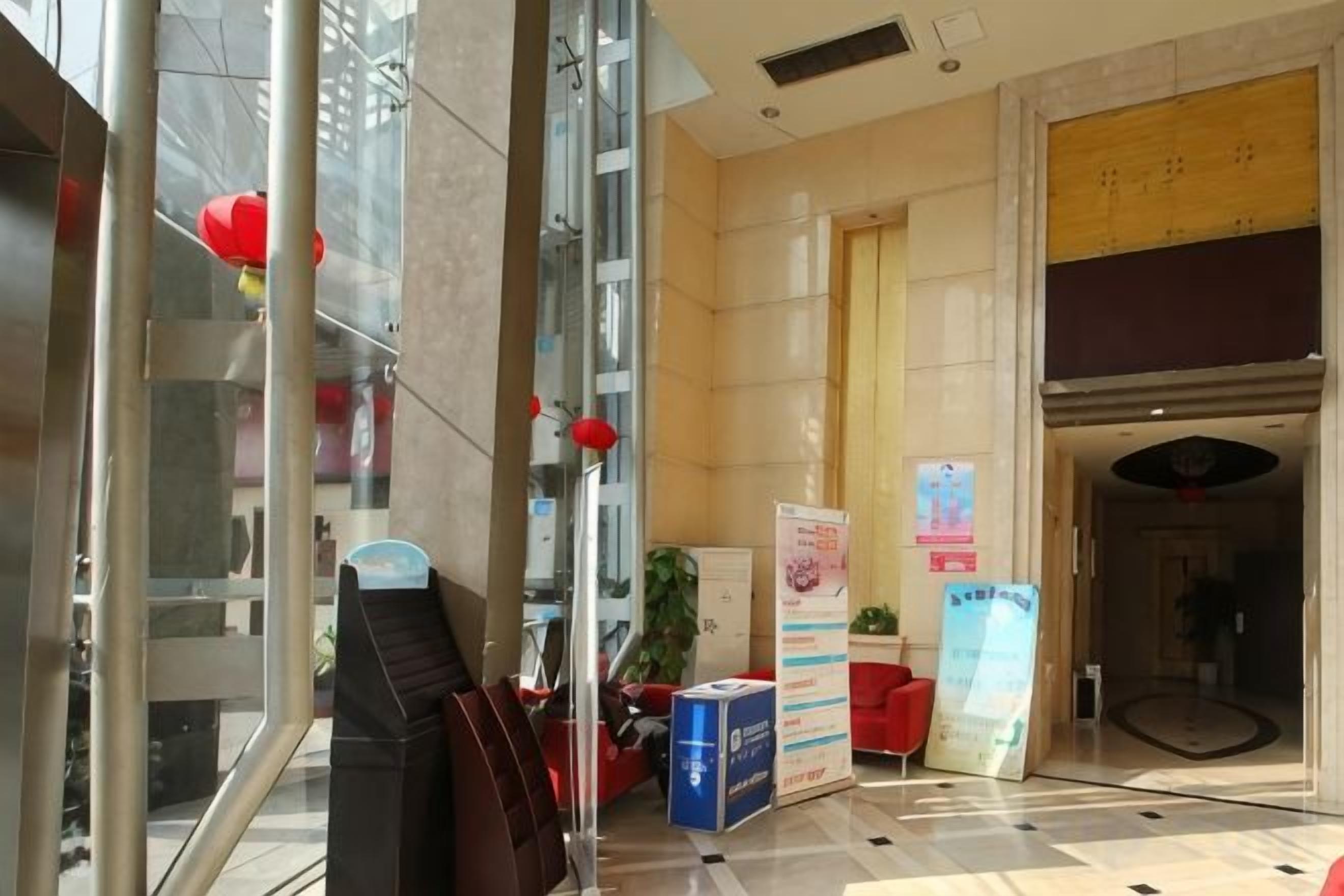 Un vestíbulo de hotel con una recepción, un espejo grande y un farol rojo.