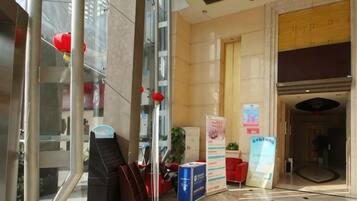 Un vestíbulo de hotel con una recepción, un espejo grande y un farol rojo.