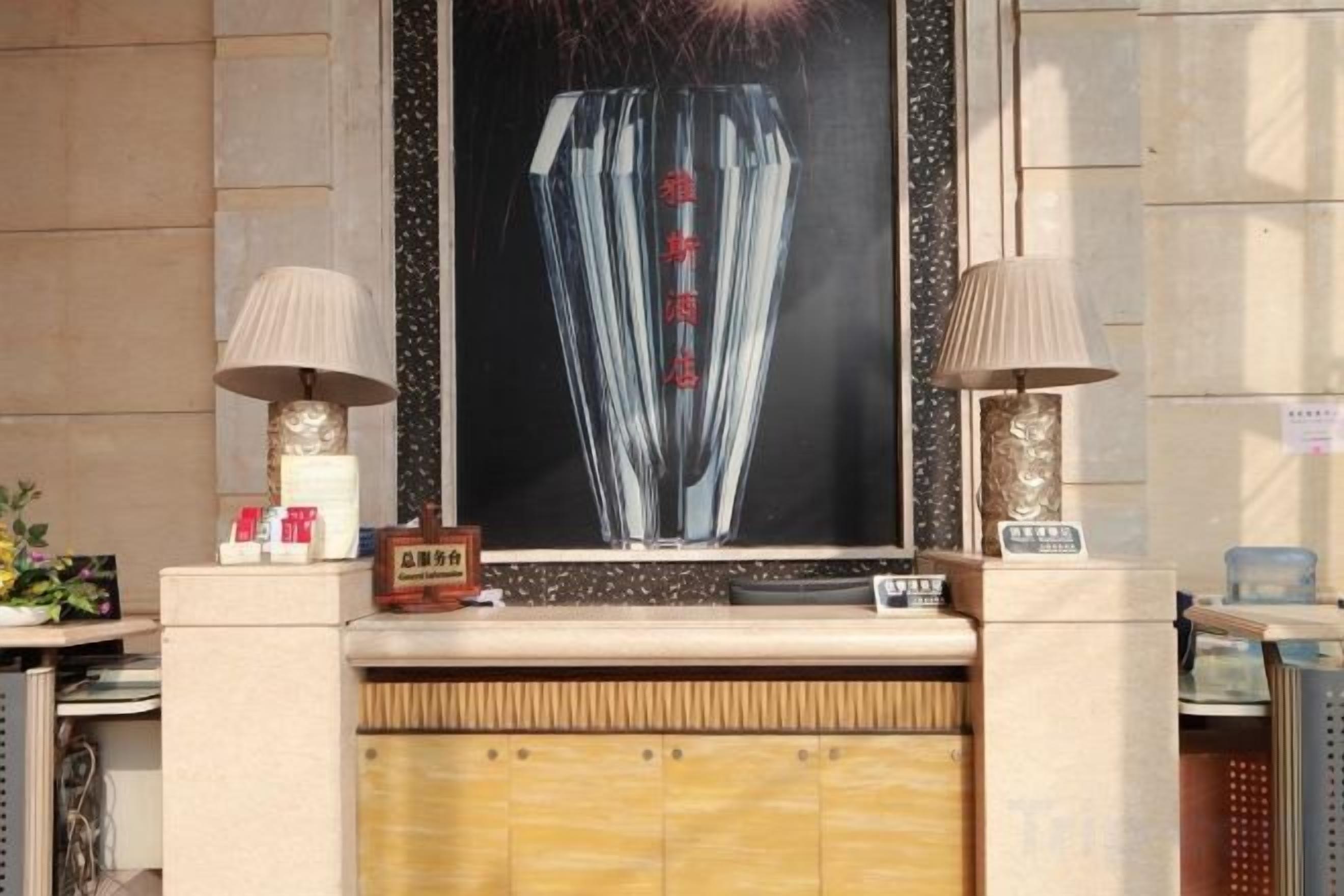 A reception desk with a framed artwork above it, a small clock, and two lamps on either side.