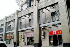 Un immeuble à plusieurs étages doté de balcons, de climatiseurs et d’enseignes.
