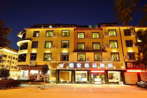 A multi-story hotel with a ground-level commercial area, featuring illuminated signage and storefronts. - Yuehong Boutique Hotel (Wuyishan)