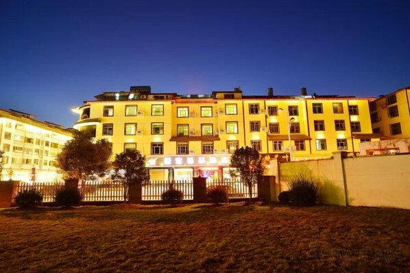 A multi-story hotel with a well-lit entrance and a fenced courtyard. - Yuehong Boutique Hotel (Wuyishan)