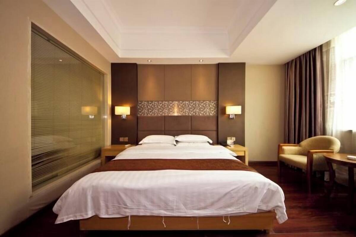 Une chambre d’hôtel avec un grand lit, deux tables de chevet, une chaise et une petite table.