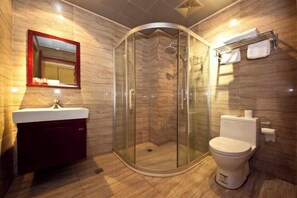 Een moderne badkamer met een glazen douchecabine, een toilet en een wastafel met spiegel.