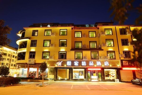 Un hotel a più piani con insegne illuminate e numerosi balconi.