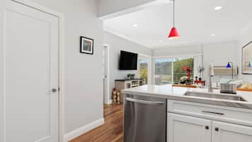 A modern kitchen with a central island, white cabinetry, and a red pendant light.