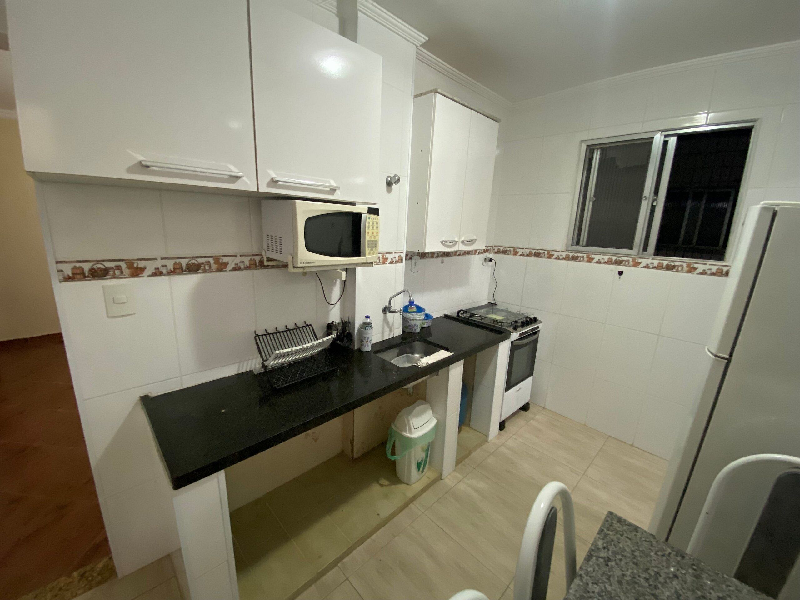 A compact kitchen with white cabinets, a microwave, a stove, and a refrigerator.