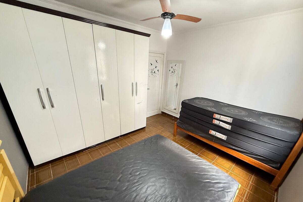 A room with a bed, wardrobe, ceiling fan, and a door with a decorative pattern.