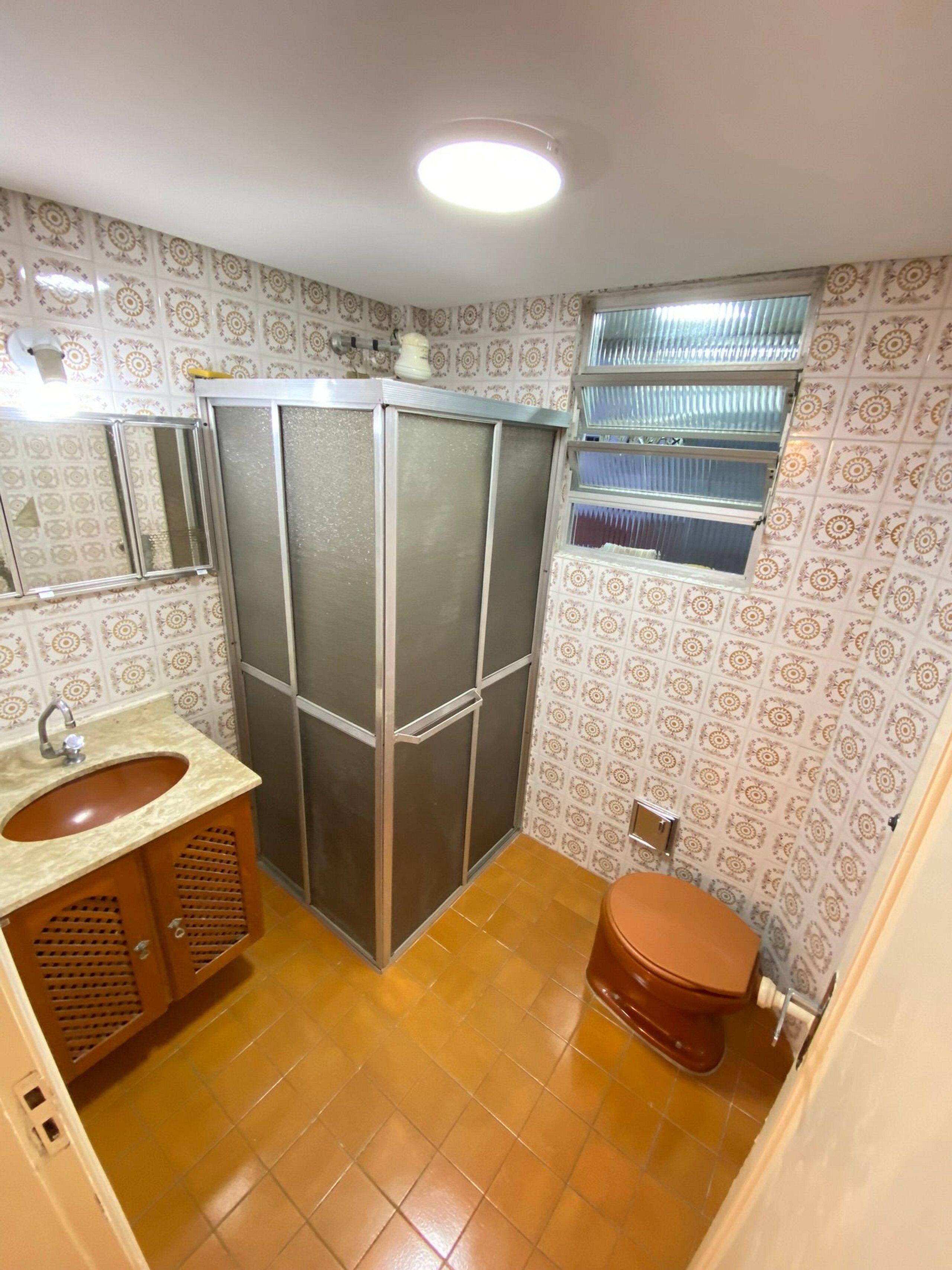 Un baño pequeño y funcional con lavamanos, inodoro y cabina de ducha.