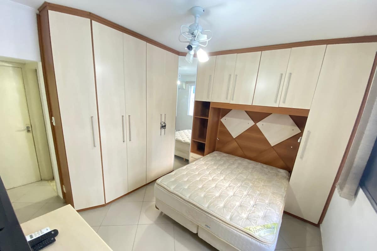 A bedroom with a bed, wardrobe, and a desk with a keyboard.