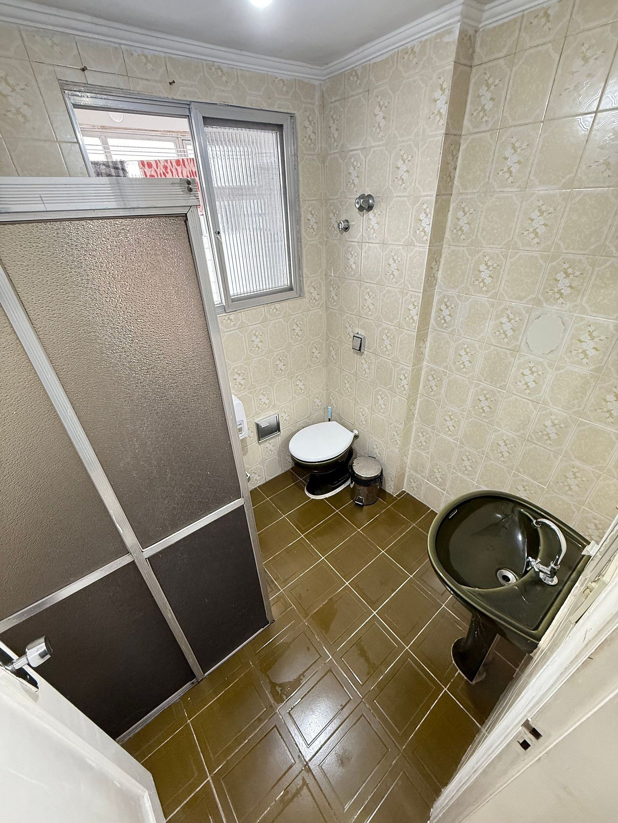 A small bathroom with a toilet, sink, and shower.
