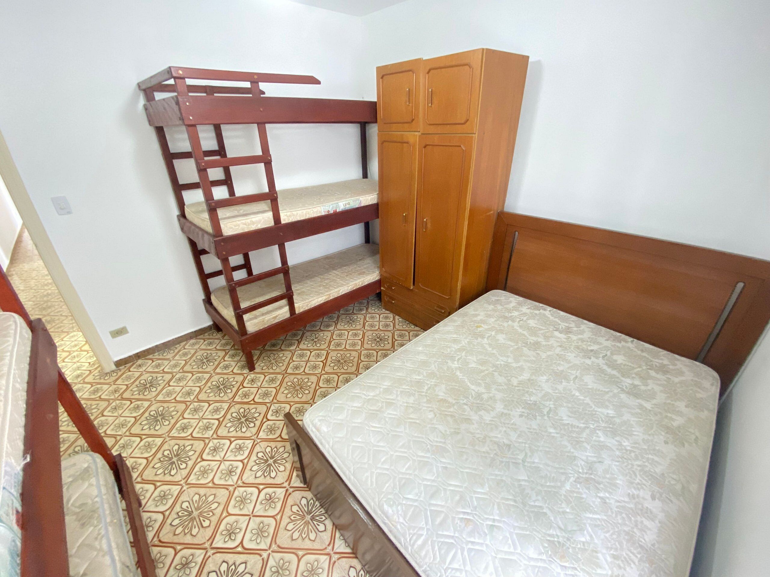 Un dormitorio con una cama alta, un armario de madera y una cama individual.