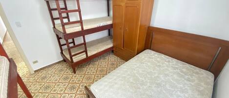 Un dormitorio con una cama alta, un armario de madera y una cama individual.