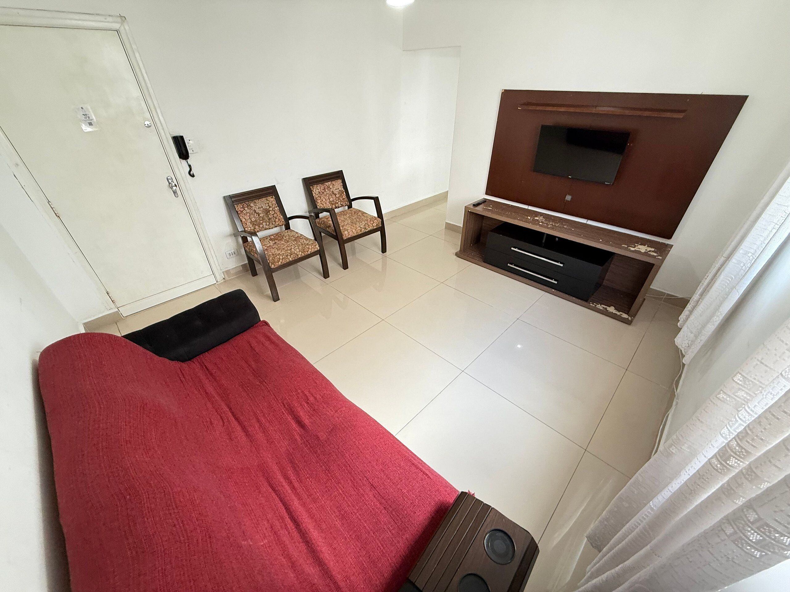 Een kamer met een bed, een televisie en twee stoelen.