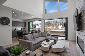 Un salon moderne avec un canapé d’angle, une table basse et un coin repas.