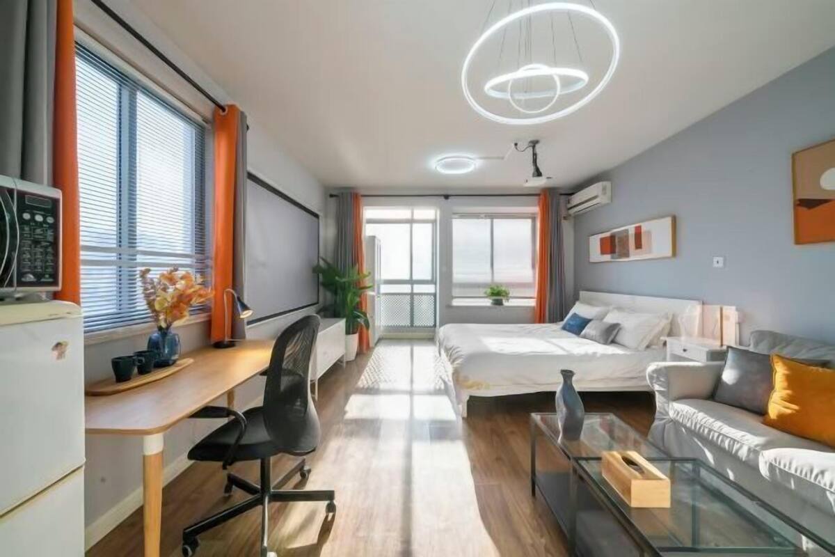 A modern bedroom with a bed, a desk, and a sofa.