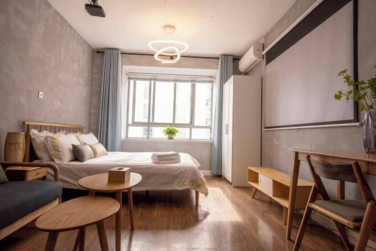 A modern bedroom with a bed, bedside tables, a desk, and a window with curtains.