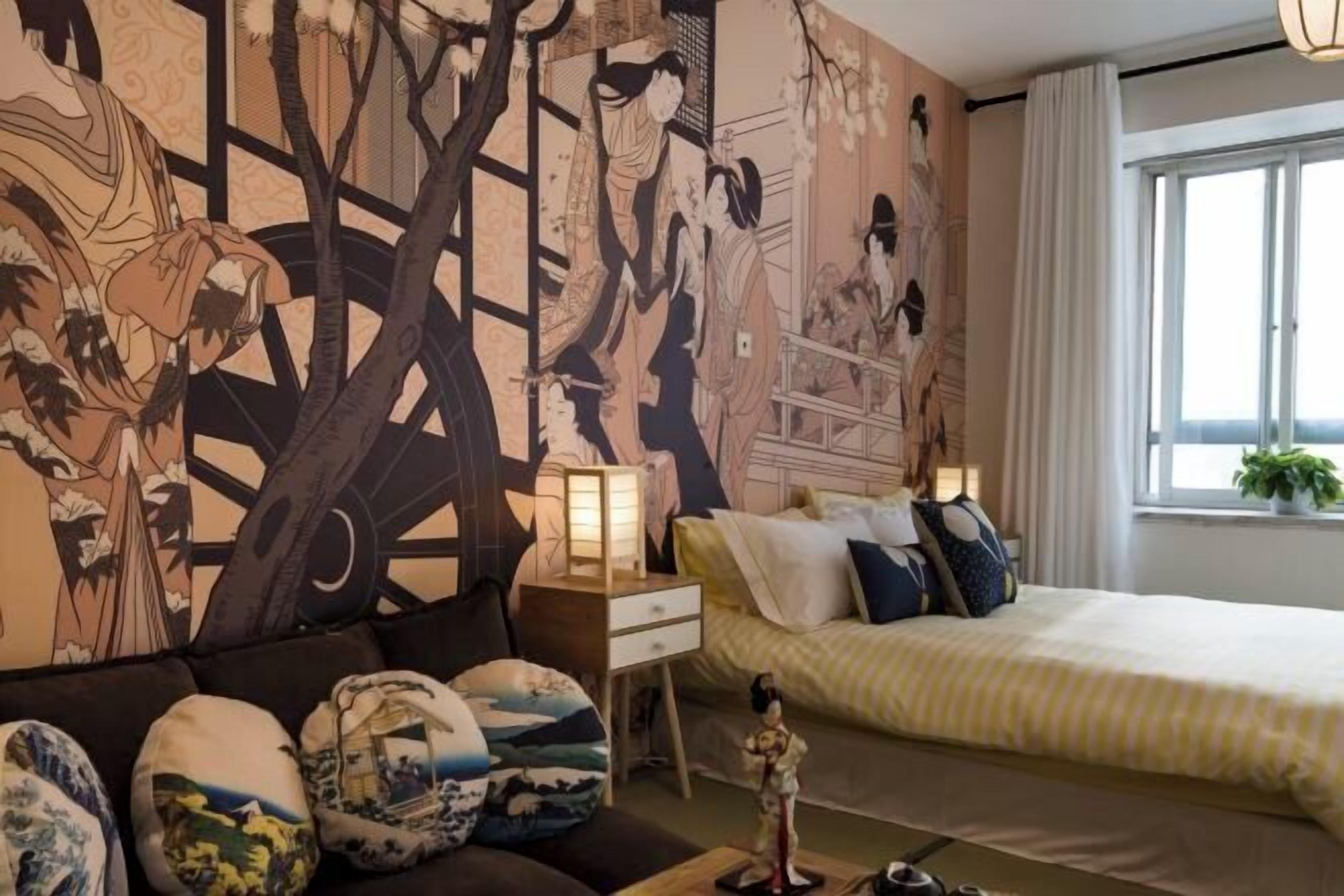 A bedroom with a large bed, a sofa, and a nightstand with a lamp.