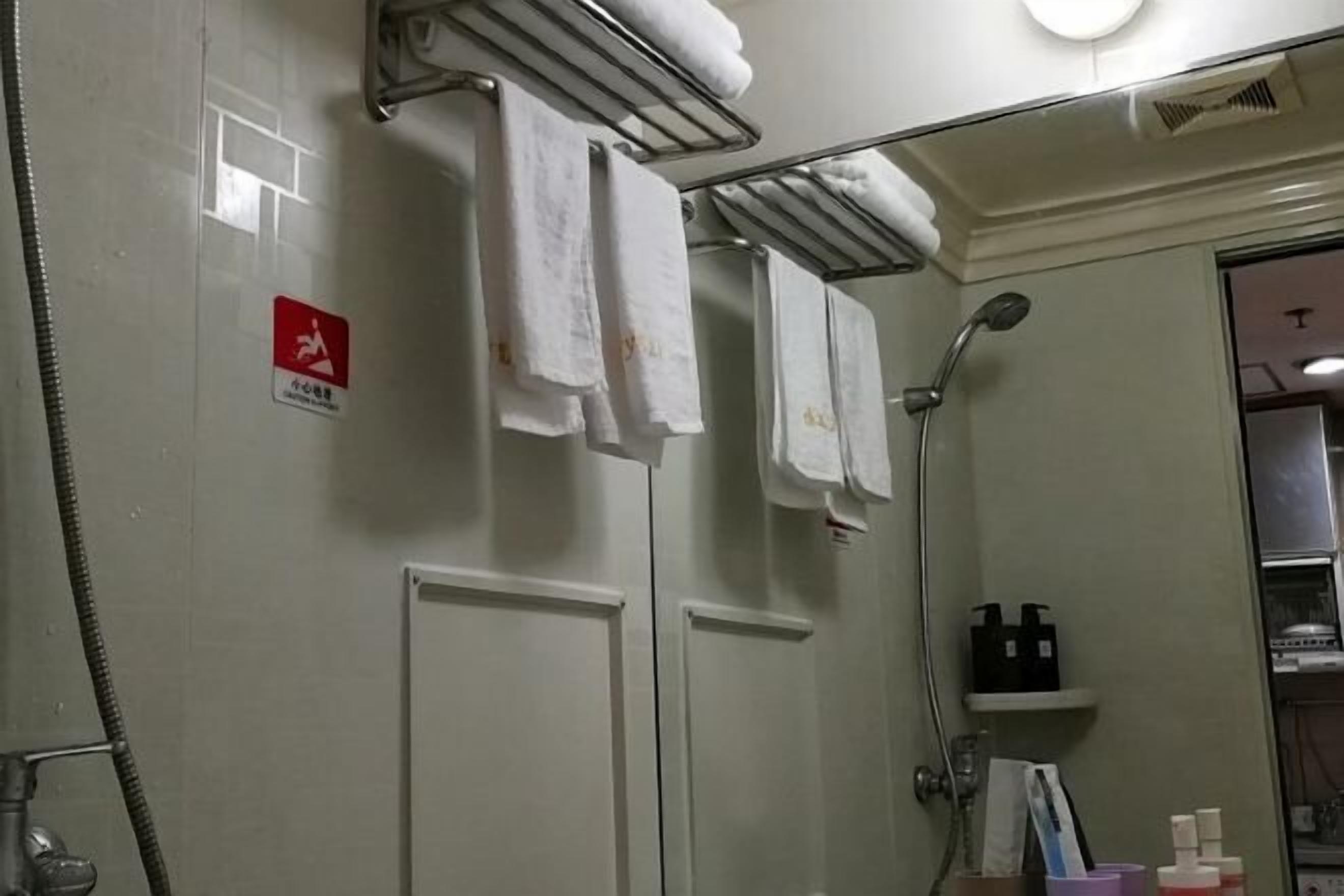 Une salle de bain équipée d’un porte-serviettes, d’une douche et d’un panneau indiquant la sortie de secours en cas d’incendie.