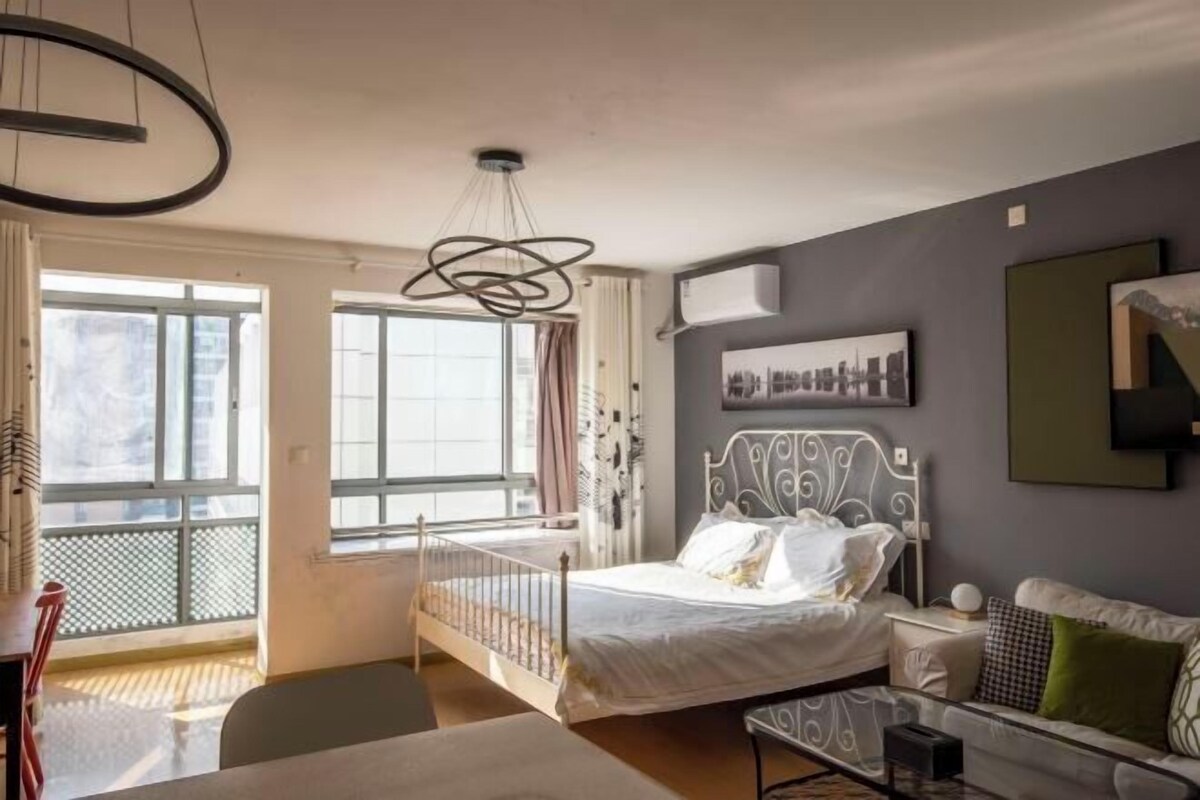 A bedroom with a bed, bedside table, and a window.