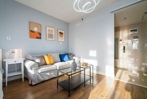 Una sala de estar moderna con un sofá, una mesa de centro de cristal y obras de arte en la pared.