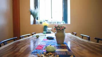 A dining table with chairs, a vase with flowers, and a window with curtains.