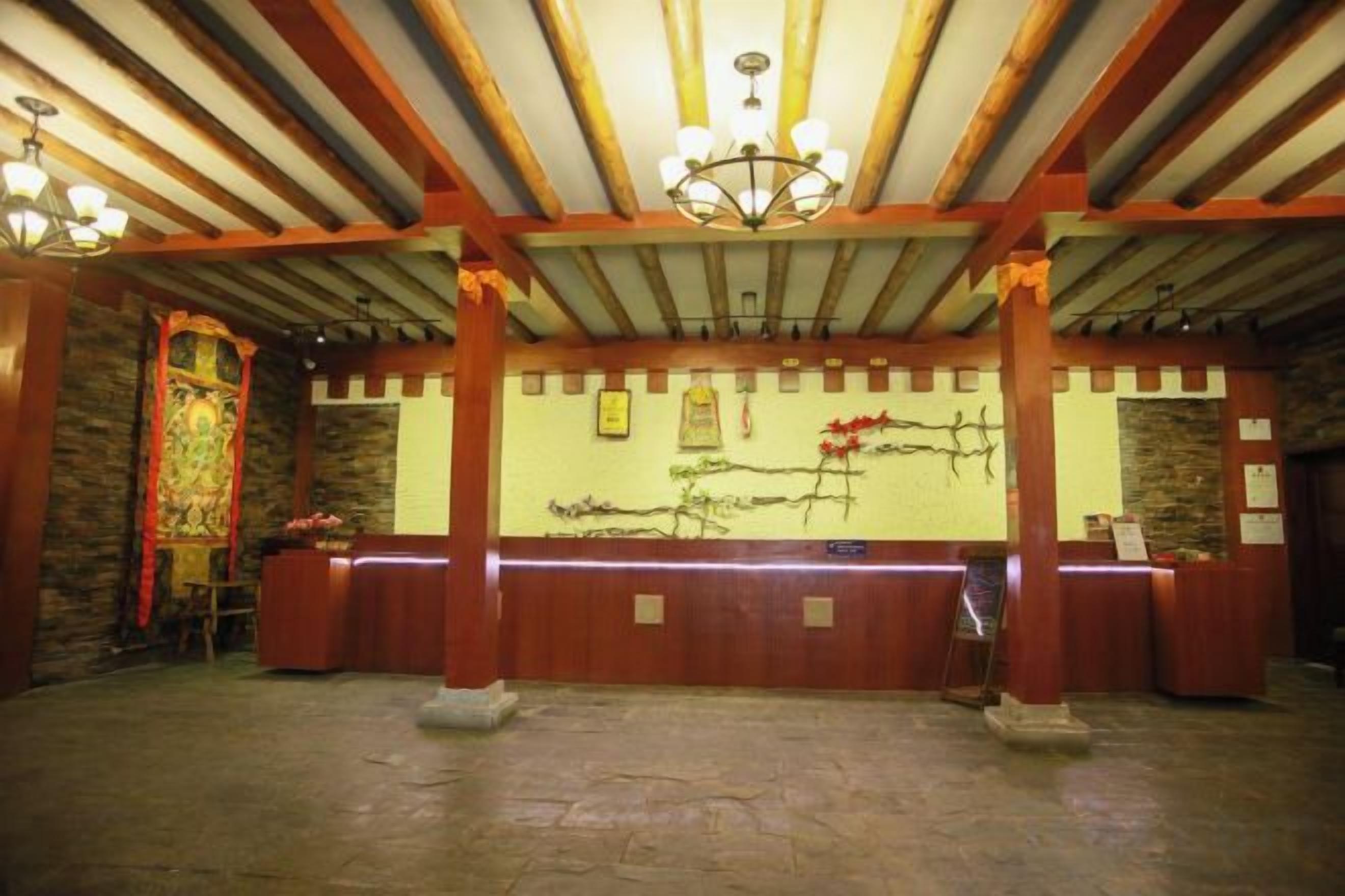 A reception area with a wooden reception desk, stone flooring, and a high ceiling with exposed beams and chandeliers.