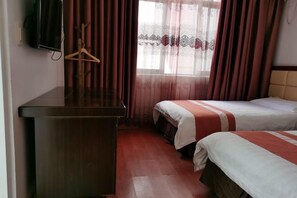 A hotel room with two beds, a wooden desk, a TV mounted on the wall, and a window with red curtains. - Yandang Mountain Baixi Hotel (Yueqing)