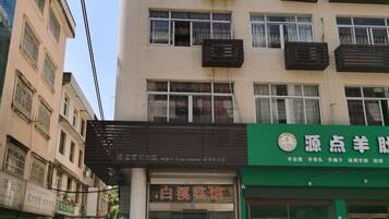 A building with multiple floors, a storefront with a green sign, and a visible entrance.