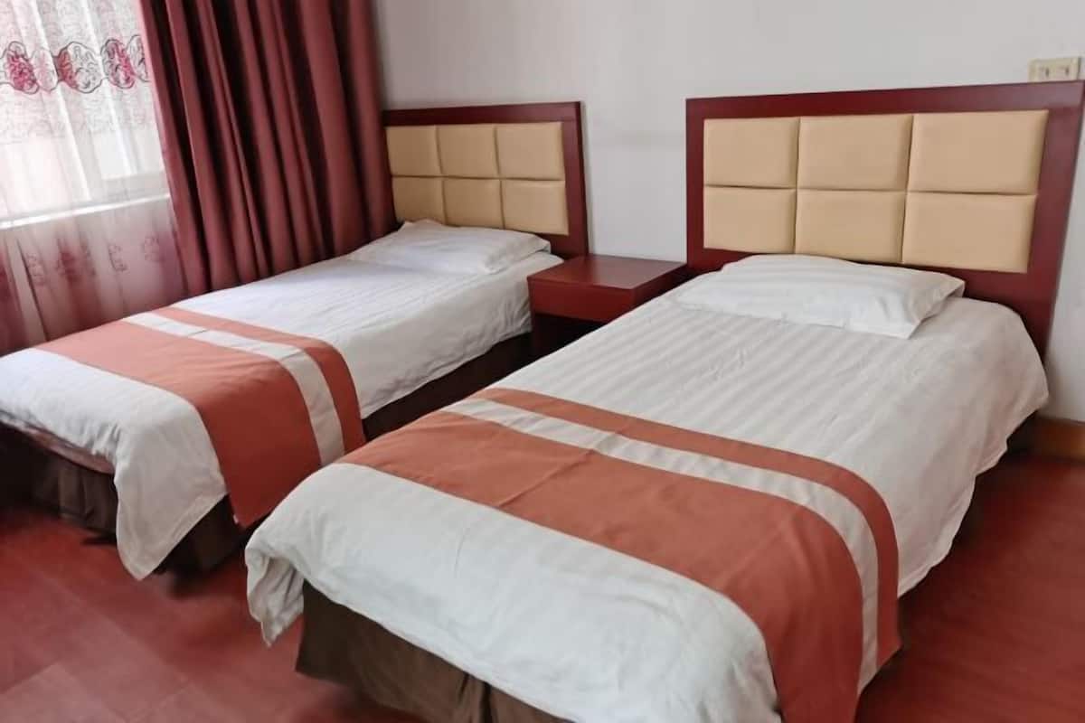 Une chambre d’hôtel avec deux lits, chacun doté d’une tête de lit et d’un pied de lit, et une table de chevet placée entre les deux.