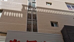 Un edificio con un letrero que dice 'Can Xiang An' en caracteres rojos sobre un fondo gris.