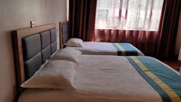 A hotel room with two beds, each with a headboard and pillows.