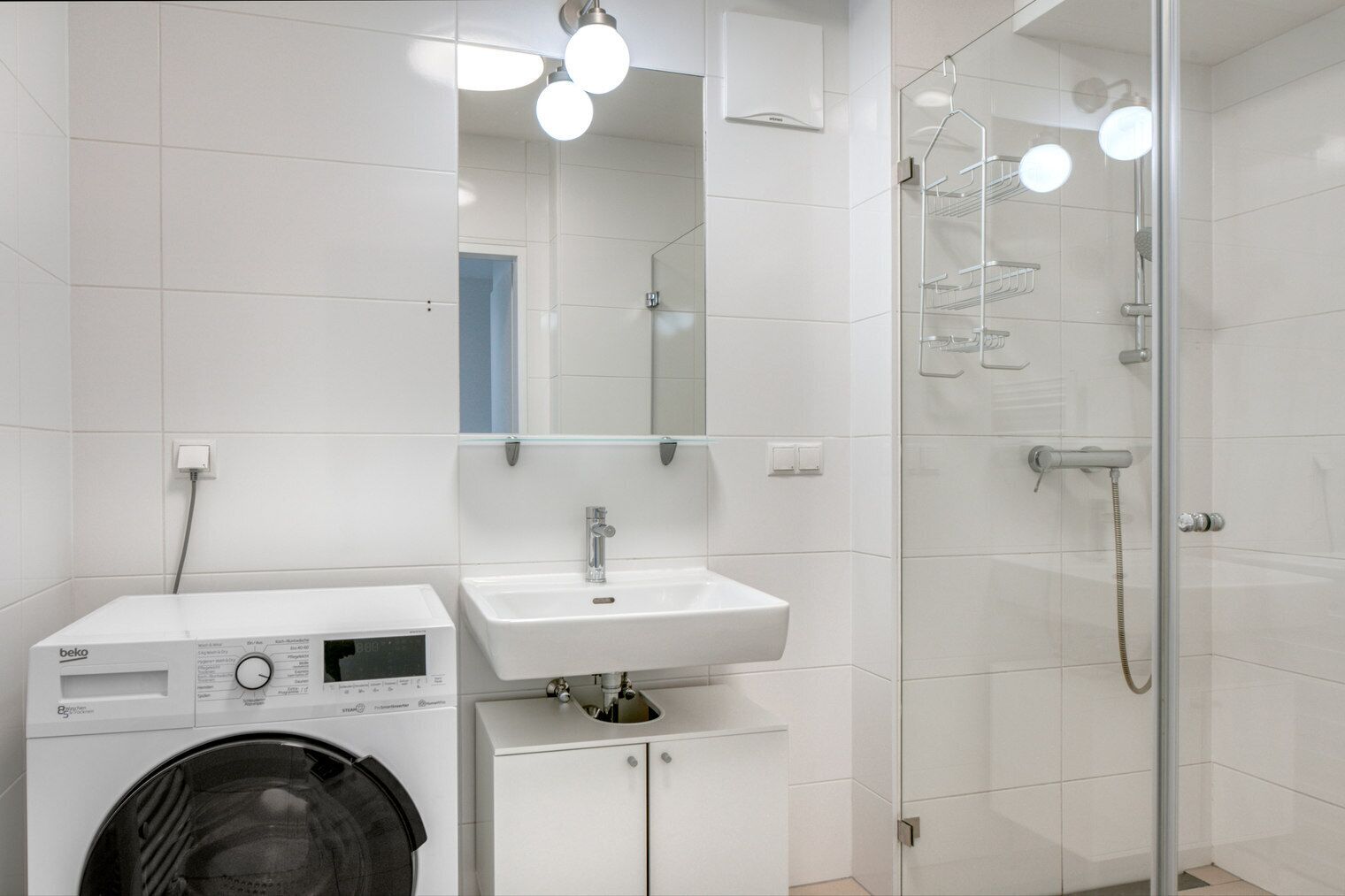 Een moderne badkamer met een wasmachine, een wastafel en een douchecabine.