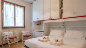 A bedroom with a bed, two chairs, a radiator, and a wardrobe. - Primula Apartment by Wonderful Italy (Bellagio)