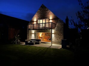 Una casa moderna con fachada de ladrillo, un balcón y un interior bien iluminado.