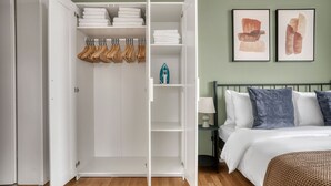 A bedroom with a bed, a nightstand, a bedside table, a wardrobe, and a wall with two framed artworks. - Modern Horgen 2.5 Room w/ Storage & W/D, 3 min to Market, by Blueground (Zurich)