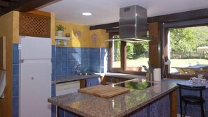 A kitchen with a built-in island, a stainless steel range hood, and a window providing a view of the outdoors. - Casa Yolanda - country house in the Picos de Europa, Arenas de Cabrales (Arenas De Cabrales)